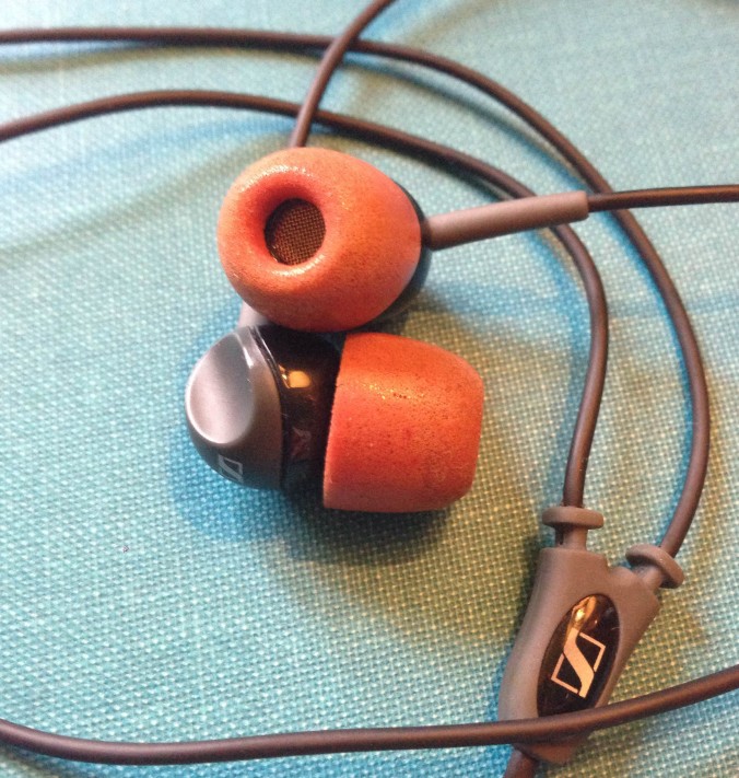 Headphones with red memory foam tips.